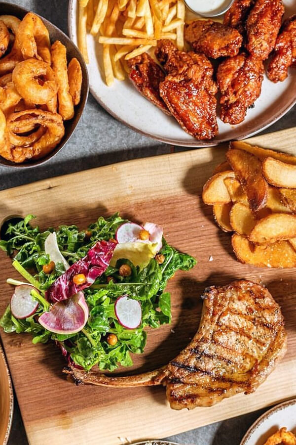 A variety of delicious dishes served at Teddy Beer bar in Toronto, including grilled meat, sandwiches, fries, and salad