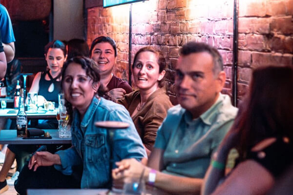 A group of happy customers enjoying their time at Teddy Beer bar in Toronto, sitting at tables and smiling