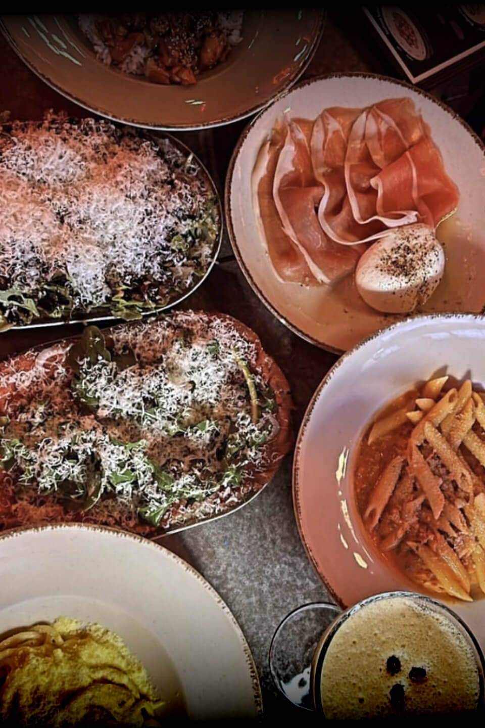 A variety of Italian dishes including pasta, salad, and prosciutto at Teddy Beer