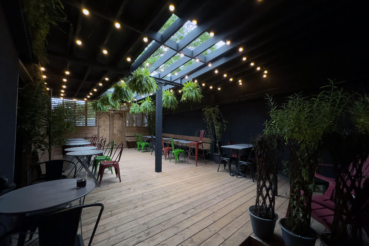 Teddy Beer Bar’s cozy outdoor patio with hanging plants and ambient lighting