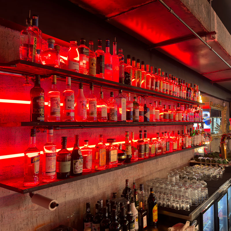 A wide selection of drinks displayed on a red-lit bar shelf at Teddy Beer