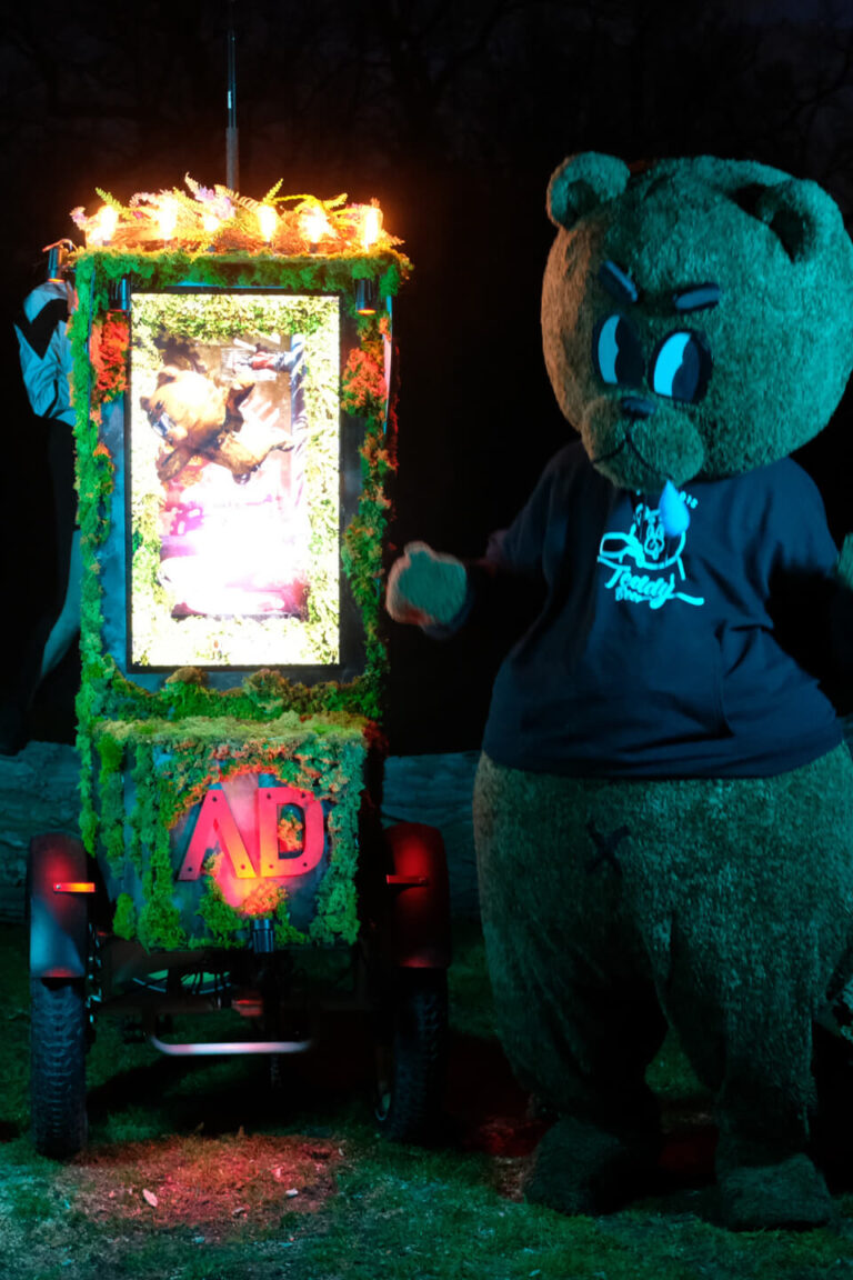 Teddy Bear mascot with an illuminated mobile display at a night event in High Park